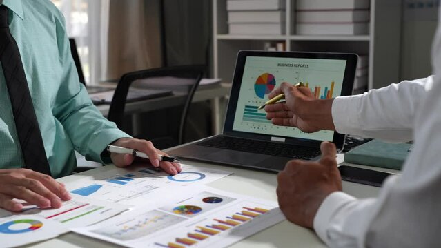 Businessman analyzing cost graphs in a conference room with a calculator and laptop with the new project of finance and accounting Presenting ideas and strategic plans at investment meetings.