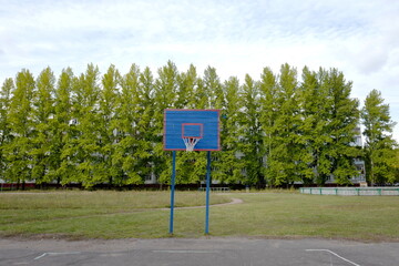 Basketball hoop on an outdoor basketball court with trees in the background