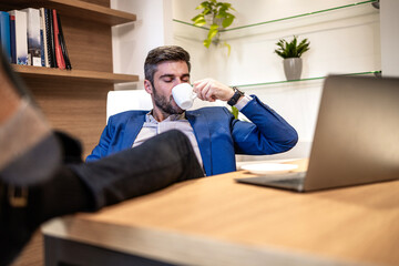 Relaxed businessman drinking in the office.