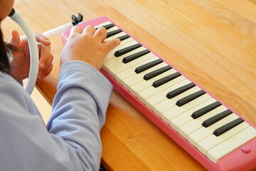小学4年生の女の子が鍵盤ハーモニカを演奏している様子。