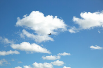 Naklejka na ściany i meble A plane in the blue sky with white clouds.