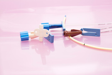Medical background: Triple lumen short-term central venous catheter with three infusion channels against light pink background - obrazy, fototapety, plakaty