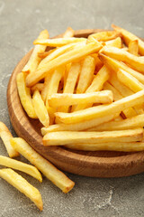 French fries on wooden plate on grey background. Top view