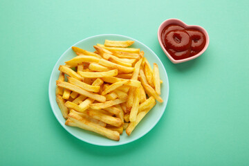 French fries with ketchup in bowl on mint background