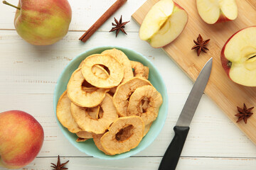 Dried apple chips with cinnamon and star anise with fresh apple. Homemade dried organic apple sliced on white wooden background.