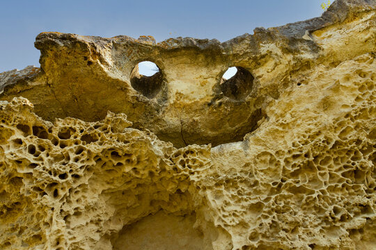 Top of the cliff in the form of a smiling face with eyes and a mouth. Texture, weathered limestone background. The bottom of the ancient sea. Abstract background.