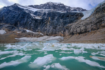 Encounter the majesty of Cavell Pond, a mountain mirrored in stillness. Witness the symphony of cascading glacier fragments, creating an arch in the emerald waters. Alberta, Canada. October 2021