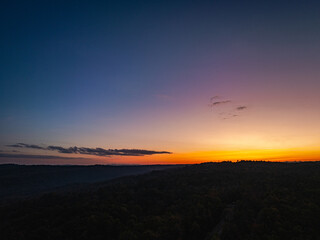 .aerial view A beautiful sunset paints the sky in vivid shades of orange .and red over a deciduous forest..Colorful leaves when the season comes to bloom in the big forest.