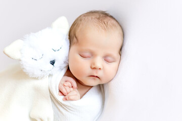 newborn baby girl in a diaper cocoon sleeping sweetly on a white isolated background with a soft...