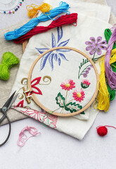 The process of hand embroidering a napkin with colored threads on white fabric.