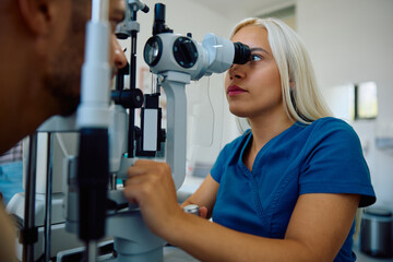 Female optometrist diagnosing eye and vision conditions of patient at clinic.