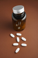 Białe tabletki rozsypane luzem z butelki z lekami - obrazy, fototapety, plakaty