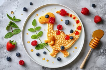 Top view of dinosaur shape made from pancakes , decorated with berries and honey. On the simple...