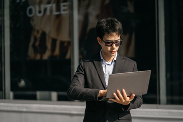 Asian male businessman use smartphone and holding laptop computer, Walk enjoy smiling while doing...