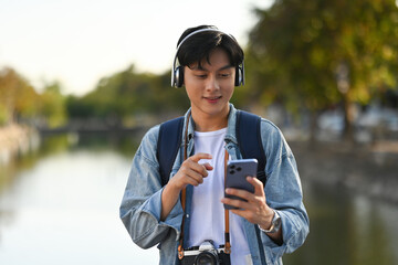Asian tourist with headphones listening to a favorite song on the phone while sightseeing the...