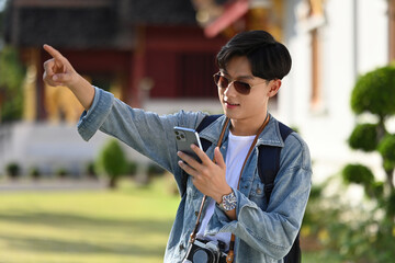 A handsome Young Asian tourist man with sunglasses looking Tourist attraction reviews on a...