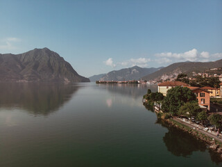 Panoramic aerial drone view of the waters of Lake Iseo in Lombardy (Italy). In the background the green mountains that surround the famous Italian lake