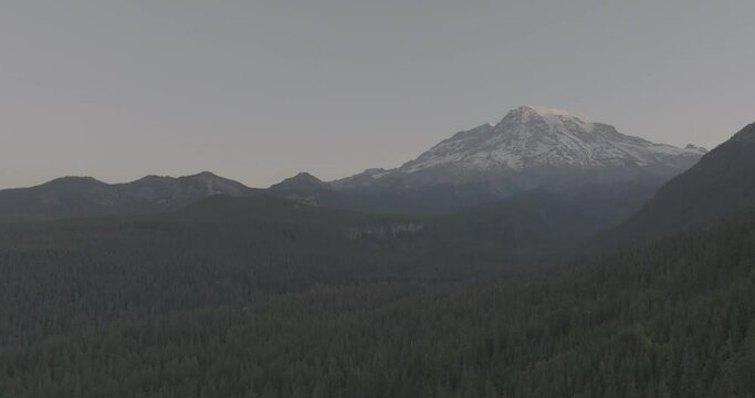 Ungraded 4k wide-angle drone footage of Mt. Rainier at dawn as the sun begins to illuminate the autumn sky above Gifford Pinchot National Forest on a sunny morning  in Washington State.