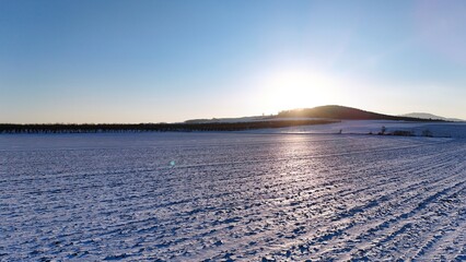 Ośnieżone wzgórze pod zachodzące słońce, zdjęcie z drona.