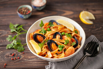 Tagliatelle pasta with mussels and shrimp in the bowl on the table. Mediterranean sea food cuisine