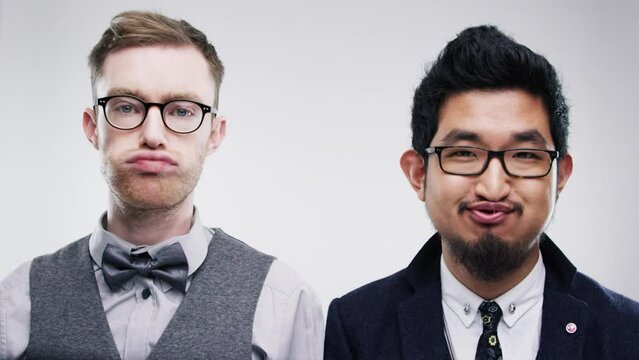 Young men, goofy face and silly in studio for crazy game, joke and lip movement for nerd humour. Friends, diversity and portrait with funny mouth and glasses for quirky geek fun by white background