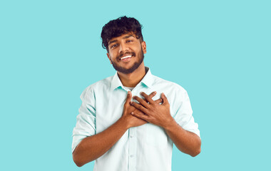 Sending you all my love. Portrait of happy Indian young man who puts his hands on his chest feeling...