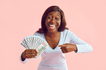 Portrait of a happy excited african american young woman pointing finger on fan of cash money...