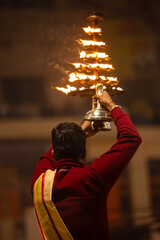Ganga aarti, Portrait of young priest performing holy river ganges evening aarti at dashashwamedh ghat in traditional dress with hindu rituals.	