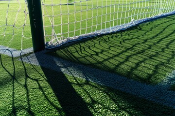 Artificial turf on football soccer field. Part of soccer goal and green synthetic grass on sport ground with shadow from goal net, Generative AI - obrazy, fototapety, plakaty