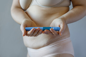 Blue Semaglutide Injection pen closeup. Semaglutide or insulin drug against female model belly....