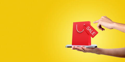 Woman hand with phone, finger touch large shopping bag on copy space