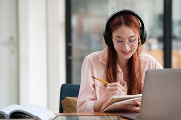 Young collage student using computer and mobile device studying online.