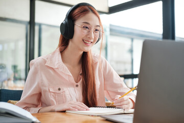 Young collage student using computer and mobile device studying online.