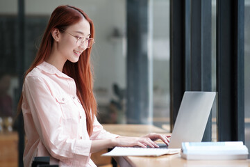 Young collage student using computer and mobile device studying online.