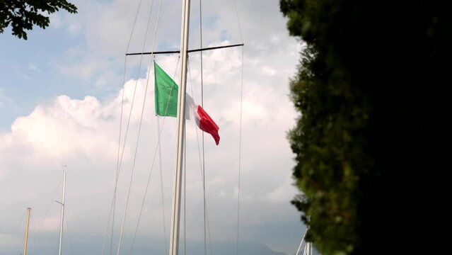 Italian tricolor flag waving while hoisted on the mast of a boat on the lake
