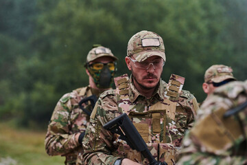 Fototapeta premium An elite military unit, led by a major, confidently parades through dense forest, showcasing precision, discipline, and readiness for high-risk operations