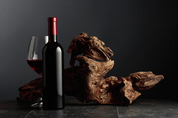 Red wine and old weathered snag on a black stone table.