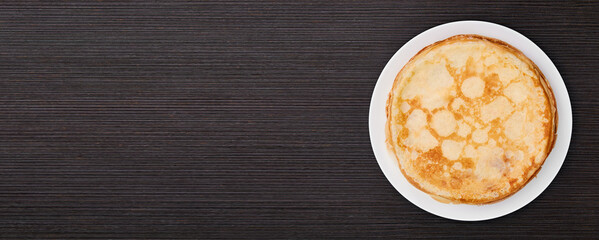 Banner of a round dish with fried pancakes on a brown table. Sweet dessert. Top view. - obrazy, fototapety, plakaty