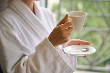 Female person having refreshing morning coffee upon awakening