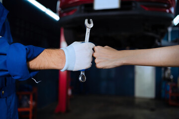 Naklejka premium Auto mechanic with wrench in garage. Engine repair and maintenance Car repairs in the garage
