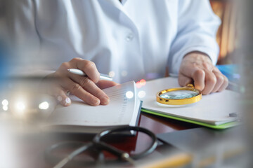 Doctor writing a prescription with a magnifying glass.
