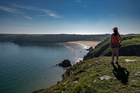Young Woman Looks Over Atlantic Coast And Barafundle Bay Beach In Wales, Pembrokeshire, United Kingdom
