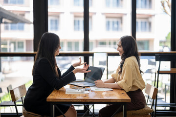 Two Asian businesswomen discuss financial management planning. Analyze new startup project ideas. Share an opinion