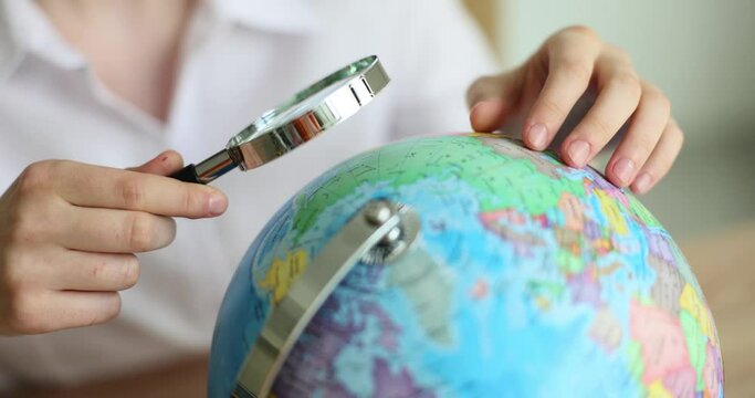 Female tourist holds globe and magnifying glass and chooses country for travel and vacation. Studying geography