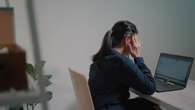 A female office worker who works in a hurry, typing quickly on a laptop computer. Before leaning back and stretching, feel your shoulders ache and relieve fatigue from sitting in a chair for a long ti