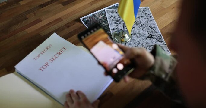 Military spy examines documents about Ukrainian counteroffensive and takes pictures with smartphone. War of Ukraine and Russia