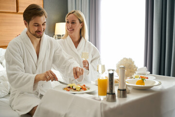 Fototapeta na wymiar Young couple communicates over breakfast in the honeymoon room