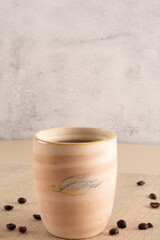 Coffee mug in a beige and stone background with coffee beans and table cloth in front view