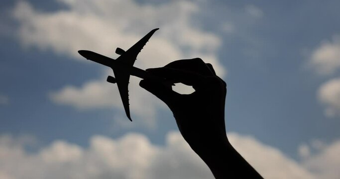Woman holds airplane in hands and flies against sky. Air travel and tourism
