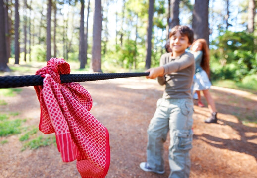 Kids, game and tug of war in forest at summer camp and holiday with travel and energy outdoor. Children with rope, adventure and team building with fun contest, playful and young friends in a park